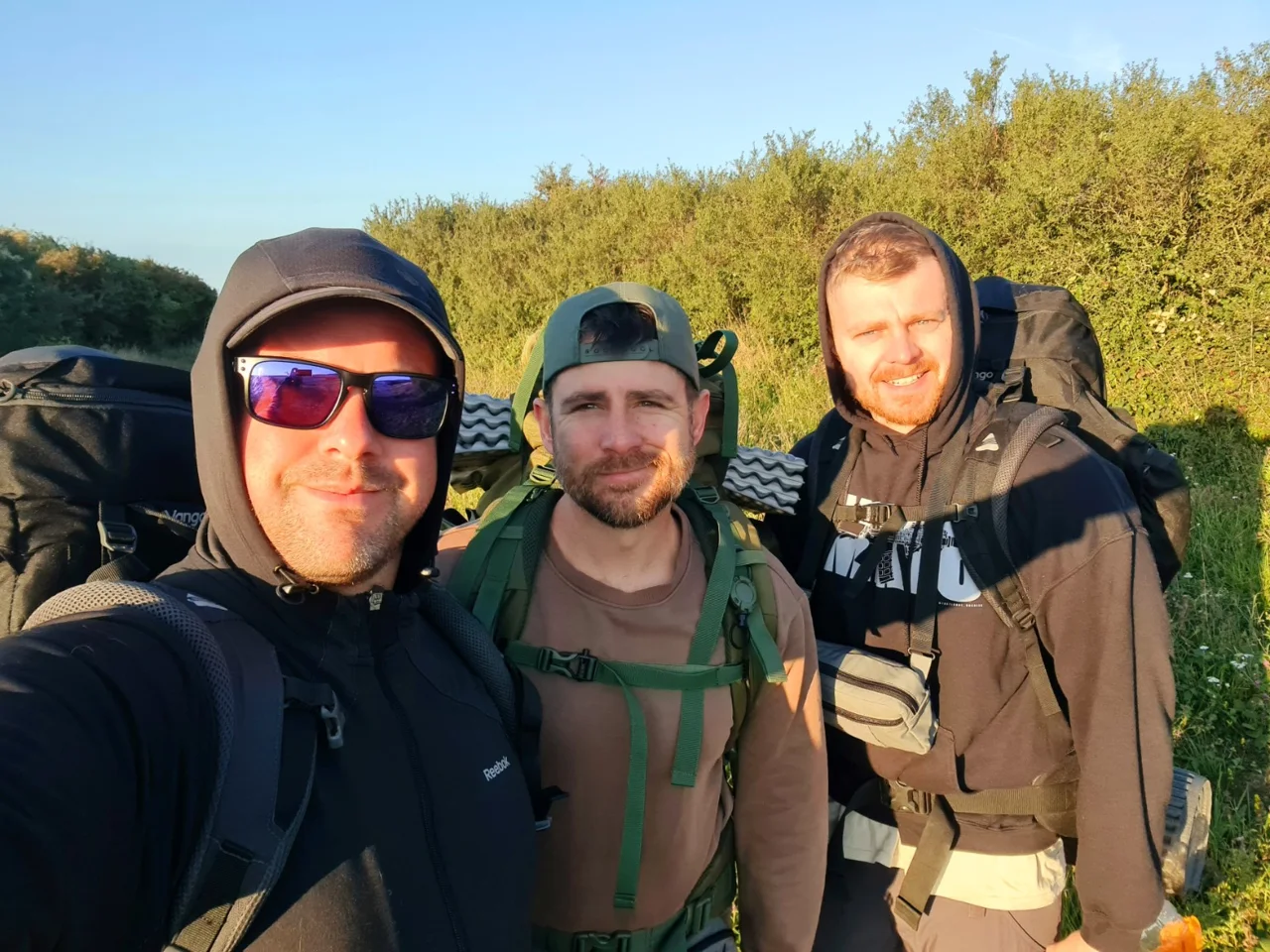 Three walkers carrying backpacks on a country path