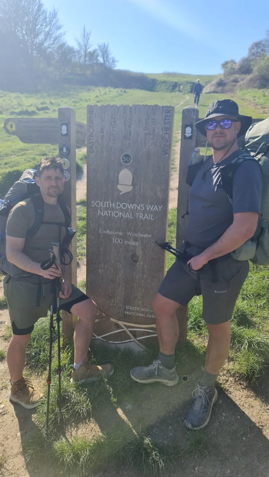 Two walkers beside a South Downs Way National Trail marker